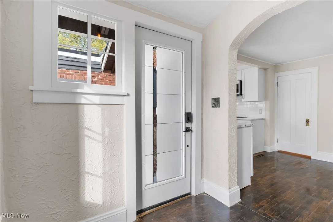 Foyer featuring dark wood-style floors, arched walkways, and a textured wall