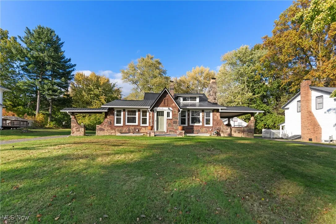 View of front facade featuring a standing seam roof, a metal roof, a front lawn, and stone siding