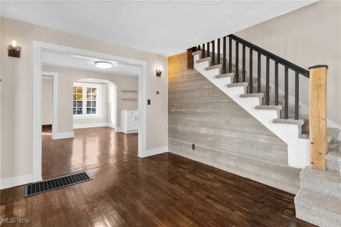 Stairway featuring wood finished floors, arched walkways, and wood walls