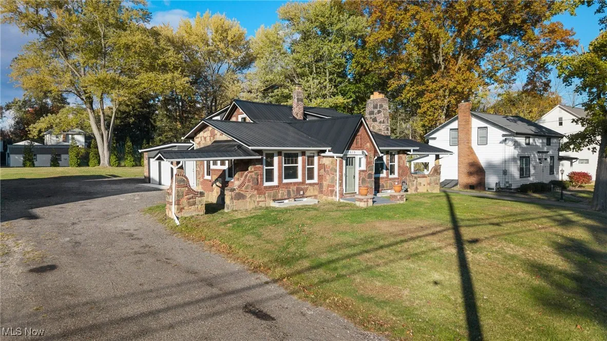 View of front of house with a front lawn, a chimney, a metal roof, and an attached garage
