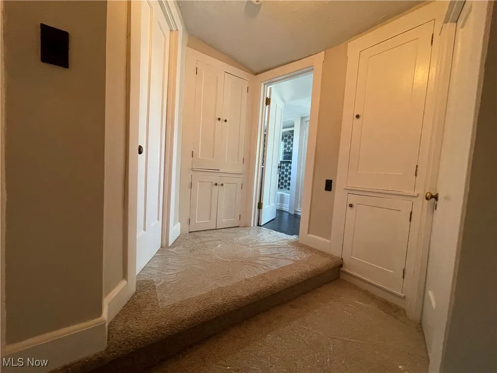 Hallway with carpet floors and baseboards