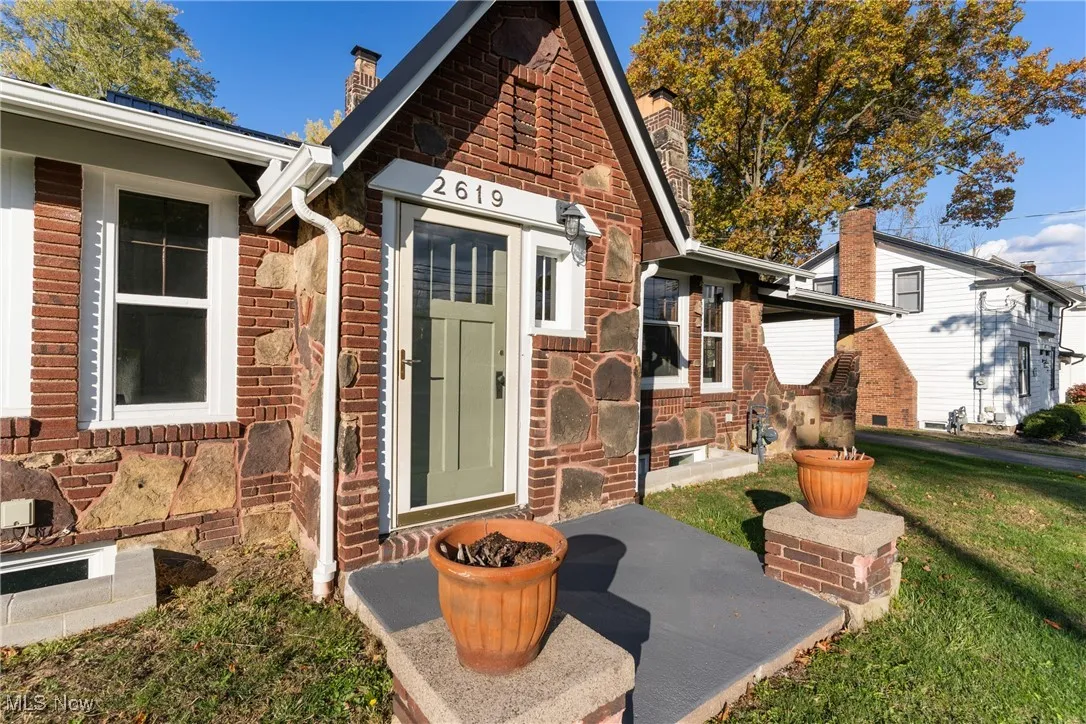View of exterior entry featuring a chimney and a lawn