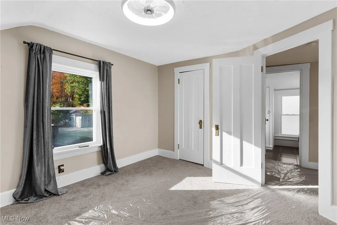 Unfurnished bedroom featuring light carpet and baseboards