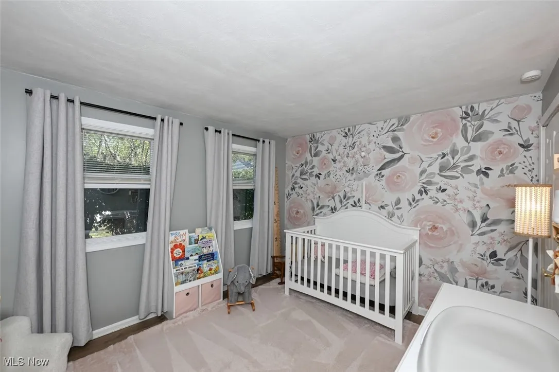 Carpeted bedroom with a nursery area and wallpapered walls