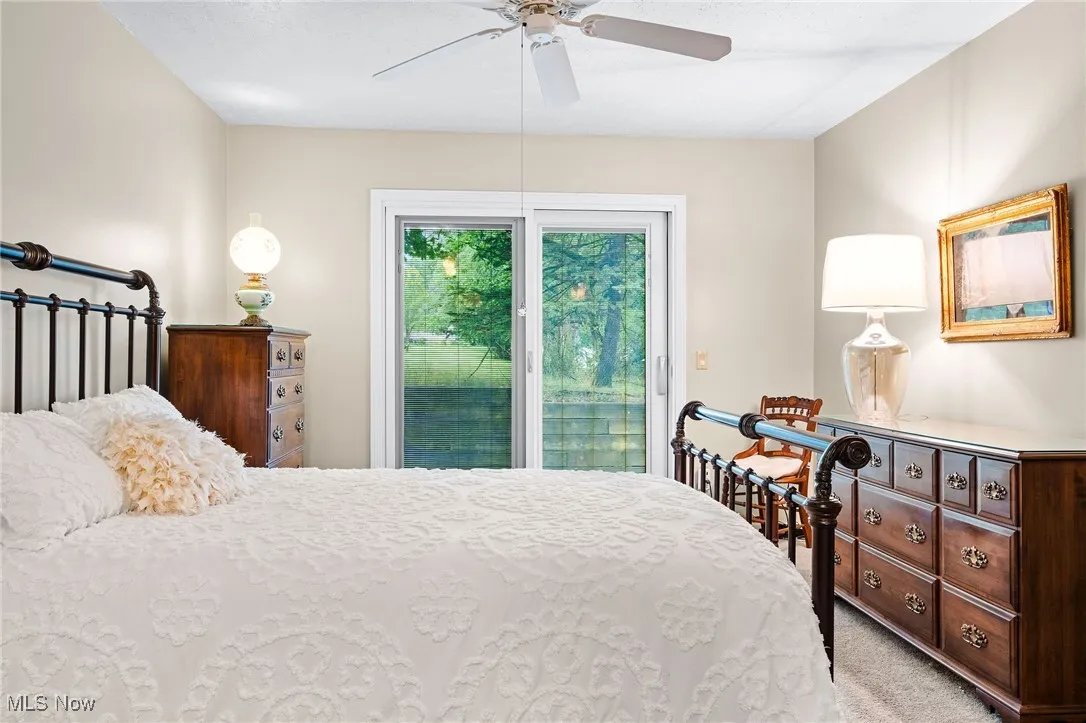 Primary bedroom with carpet floors, ceiling fan, and access to exterior
