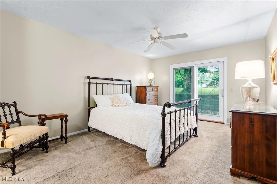 Primary bedroom with light carpet, a ceiling fan, access to outside, and a textured ceiling