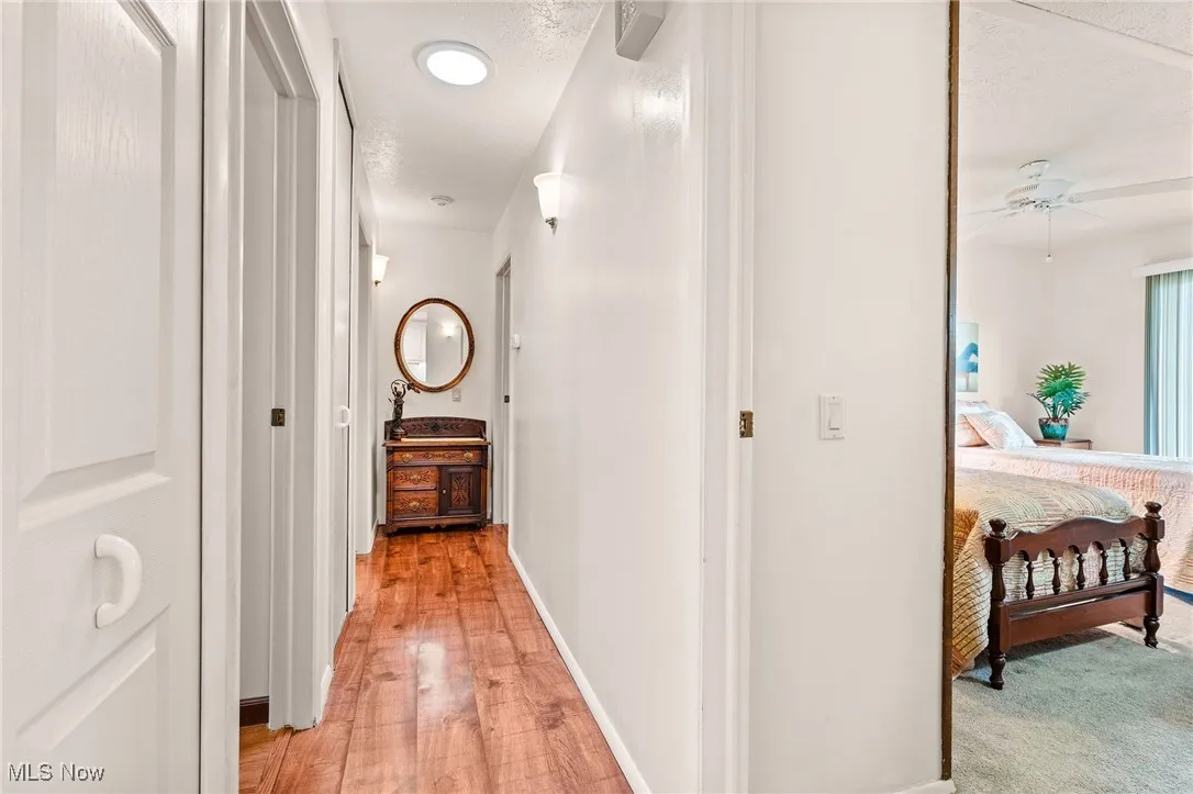 Hallway featuring a textured ceiling with solar tube for additional lighting and light wood-type flooring