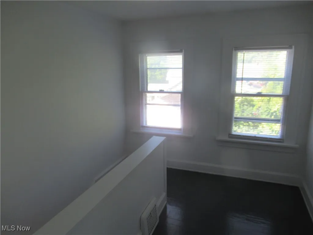 Corridor featuring dark wood-style flooring and baseboards