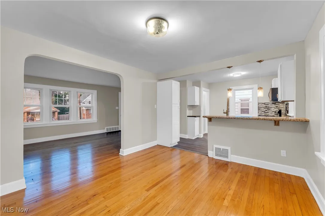 Unfurnished living room with arched walkways and light wood finished floors
