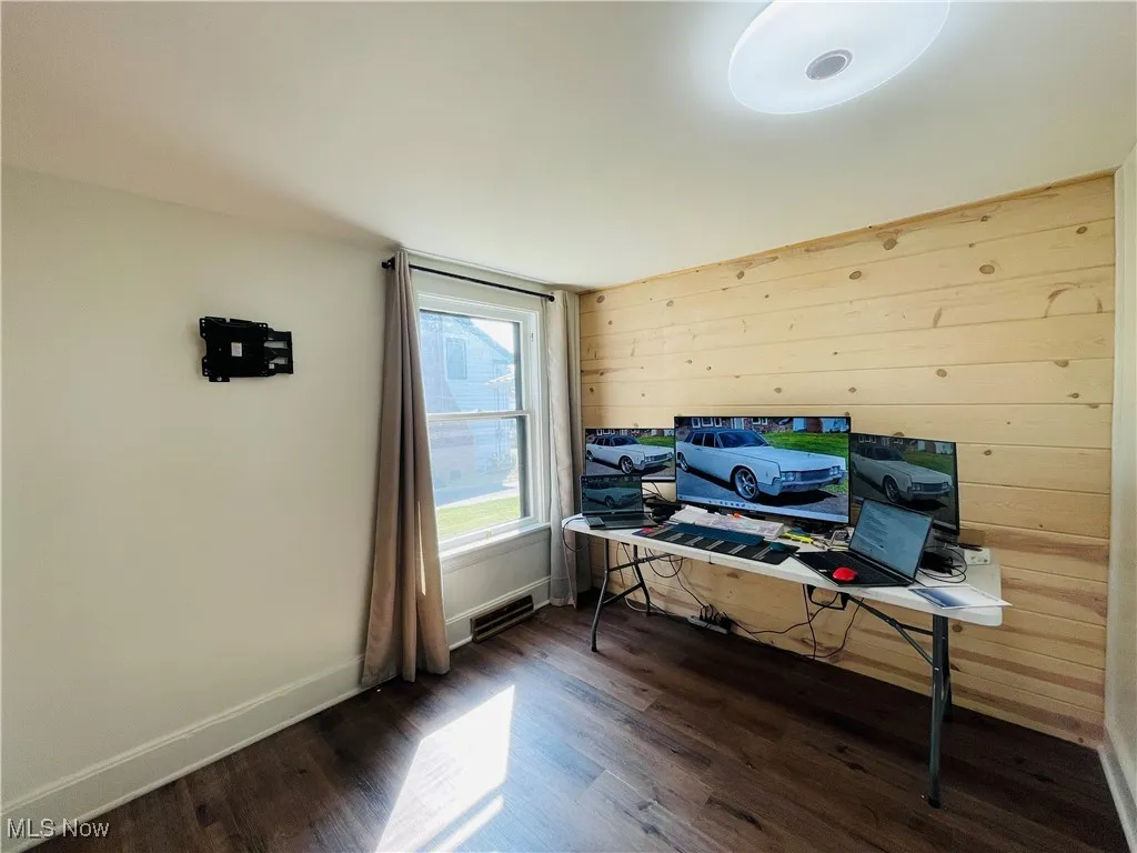 Office space featuring wooden walls and dark wood-type flooring