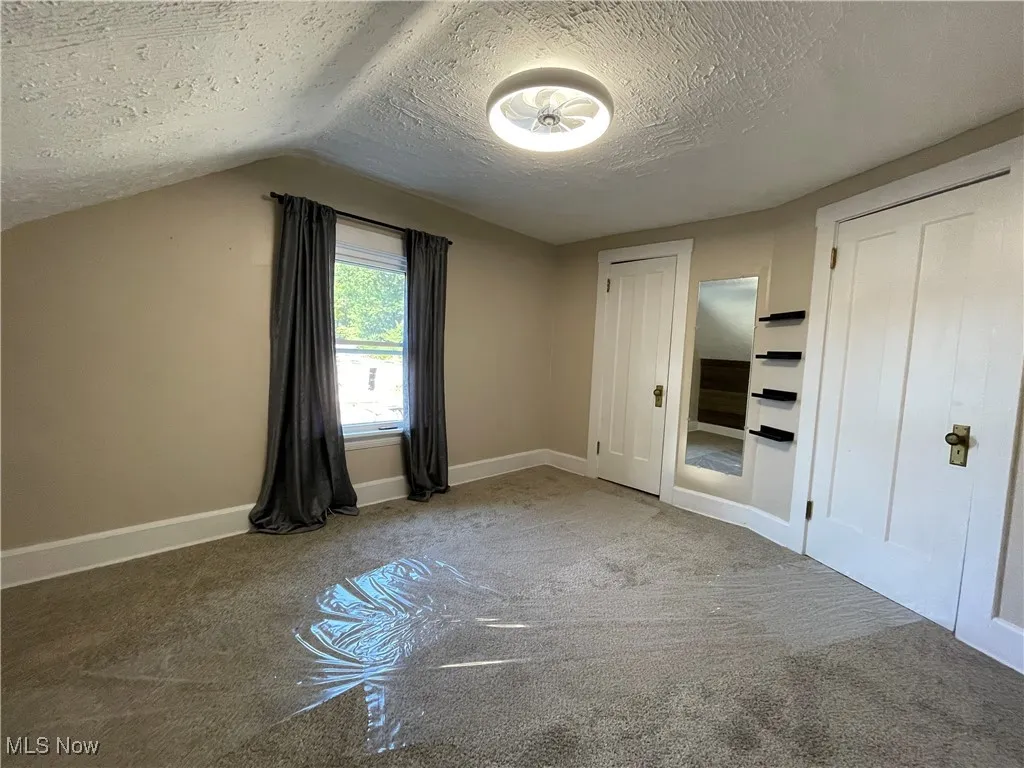 Unfurnished bedroom featuring a textured ceiling, two closets, and carpet floors