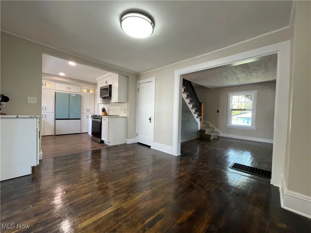 Unfurnished living room with dark wood-type flooring, stairs, and recessed lighting