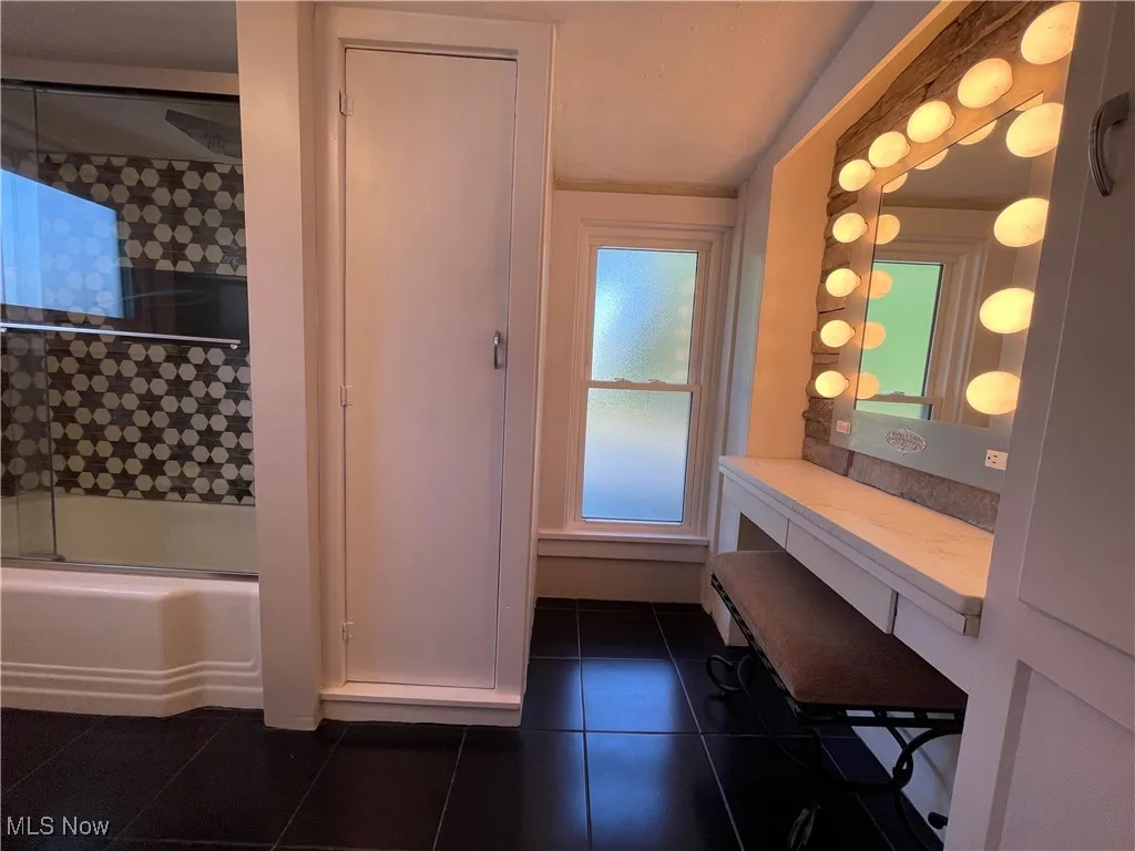 Full bathroom featuring bath / shower combo with glass door and dark tile patterned floors