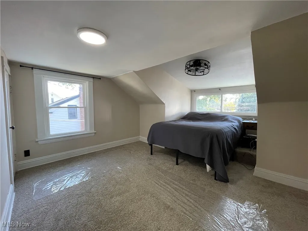 Bedroom featuring multiple windows, vaulted ceiling, and light colored carpet