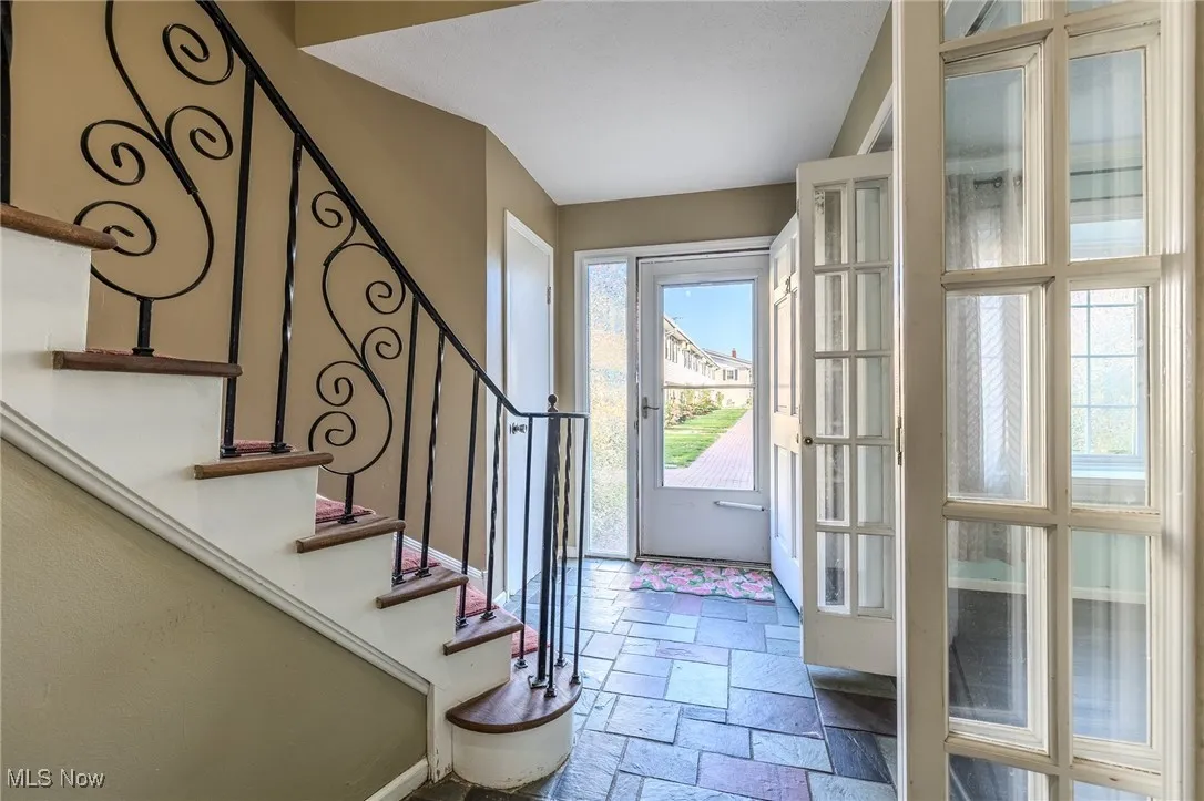Doorway to outside with stone tile flooring and stairs