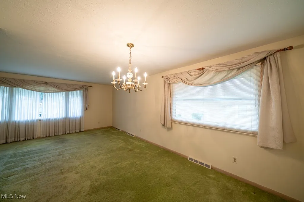 Unfurnished dining area with a chandelier and carpet flooring