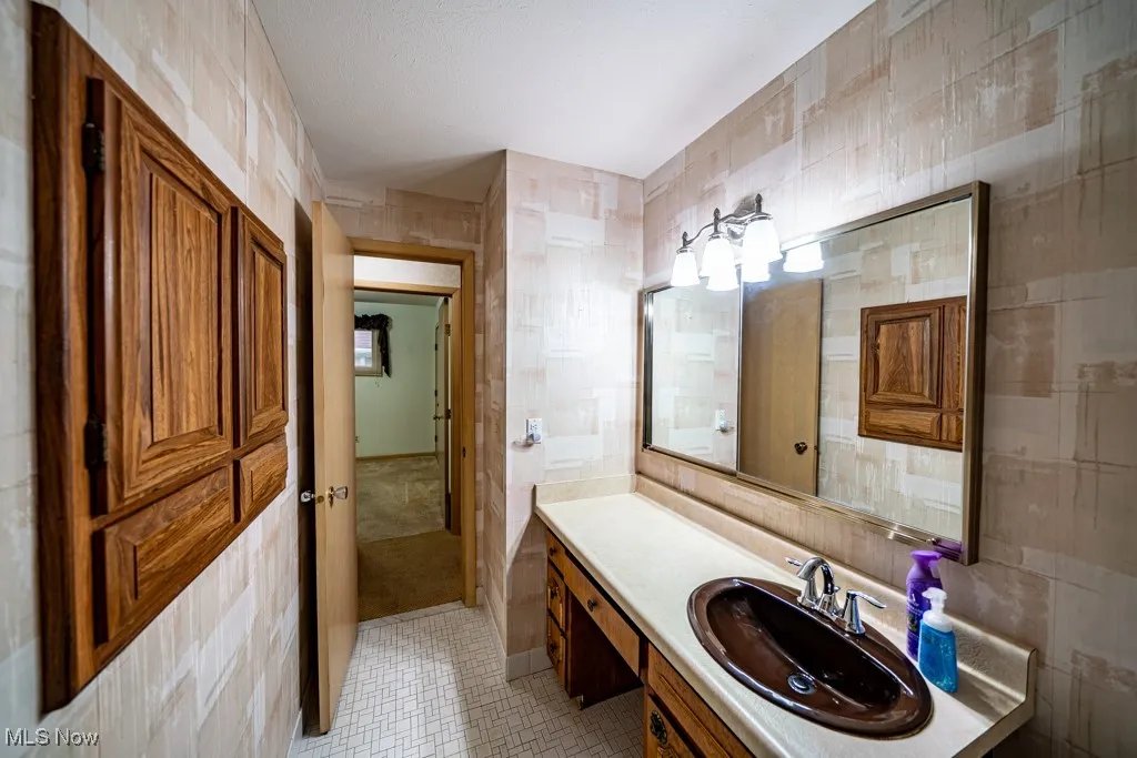 Bathroom with tile walls, vanity, and light tile patterned floors