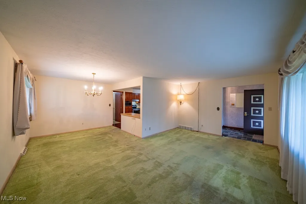 Unfurnished living room with carpet flooring and a chandelier