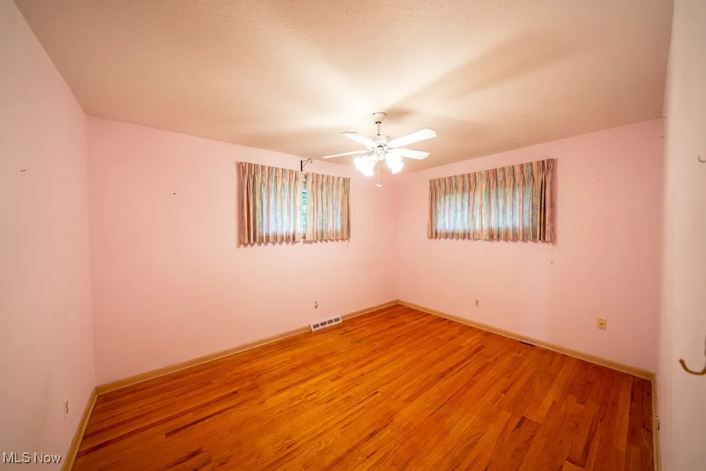 Spare room featuring wood finished floors and a ceiling fan