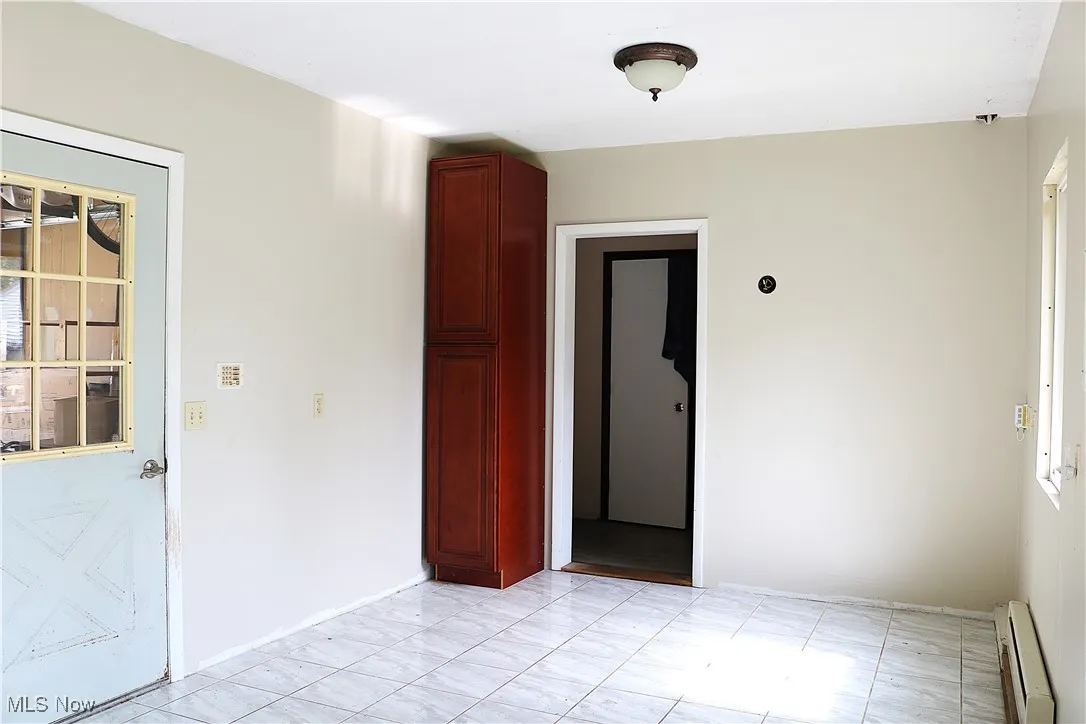 Unfurnished room with a baseboard heating unit and baseboards