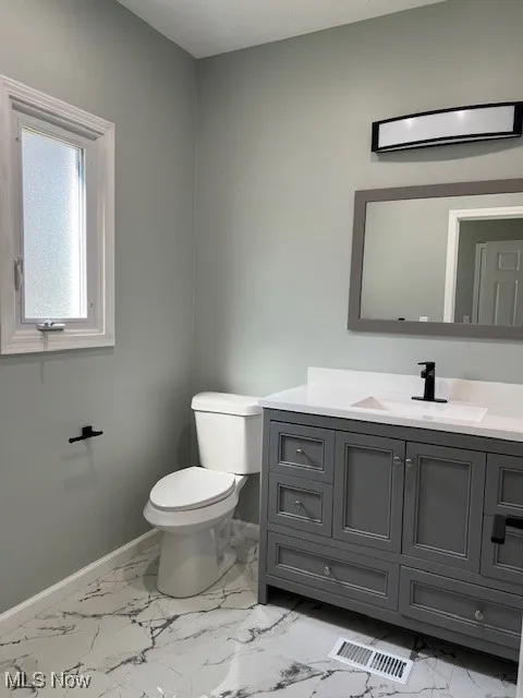 Bathroom featuring vanity, light marble finish flooring, and a wall mounted AC