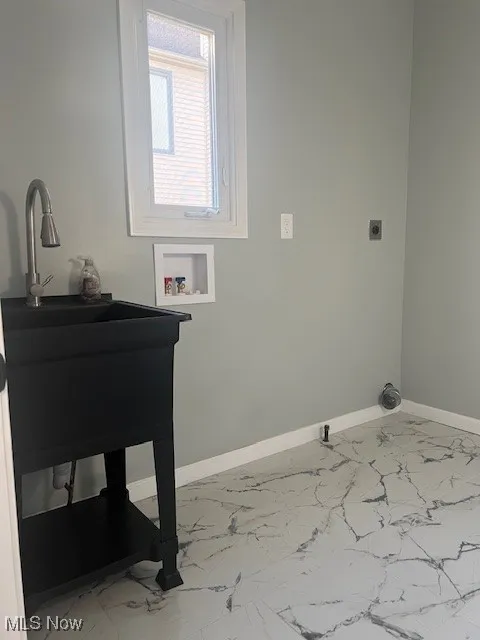 Laundry room featuring light marble finish floors, hookup for a washing machine, and hookup for an electric dryer