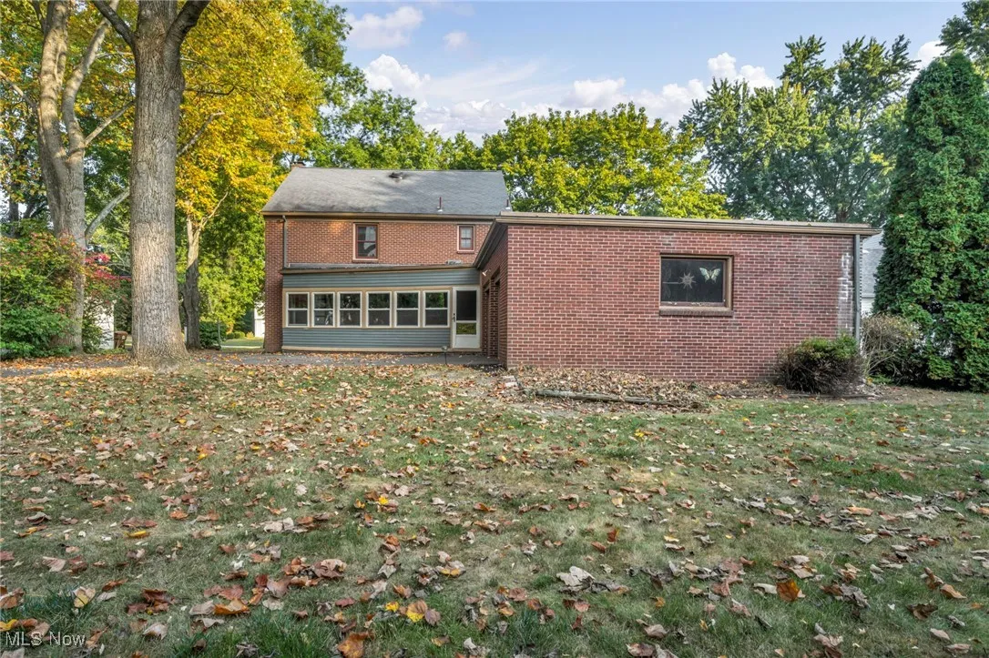 Rear view of house with a yard, brick siding, and a sunroom