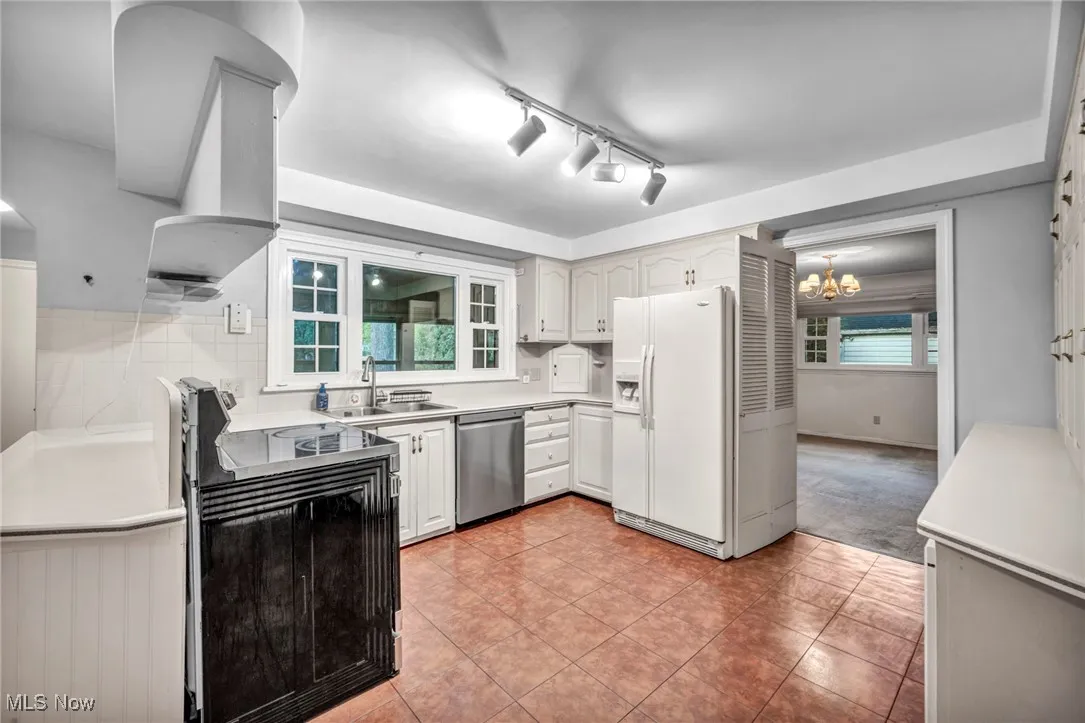 Kitchen with healthy amount of natural light, white refrigerator with ice dispenser, range, and light countertops