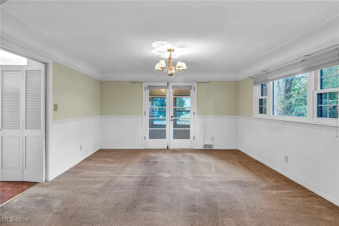 Dining area featuring carpet floors, a chandelier, and french doors