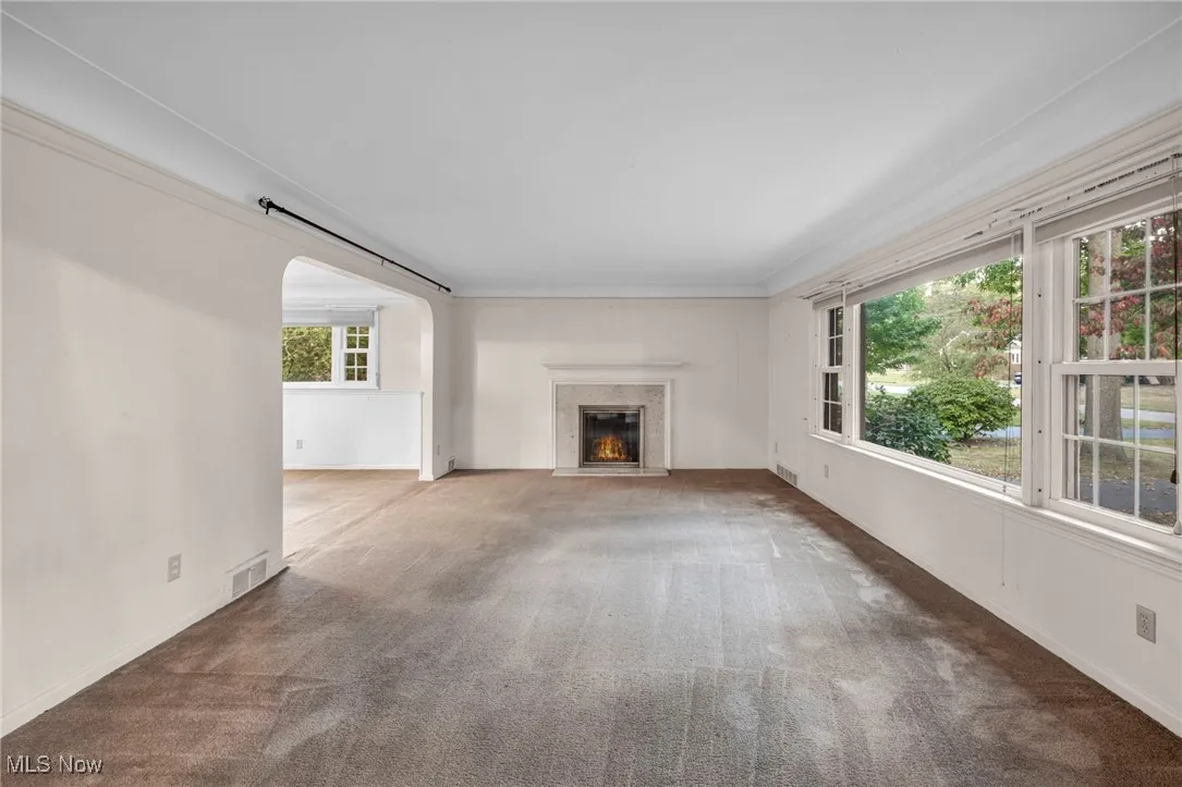  Living room featuring carpet flooring, a high end fireplace, and arched walkways