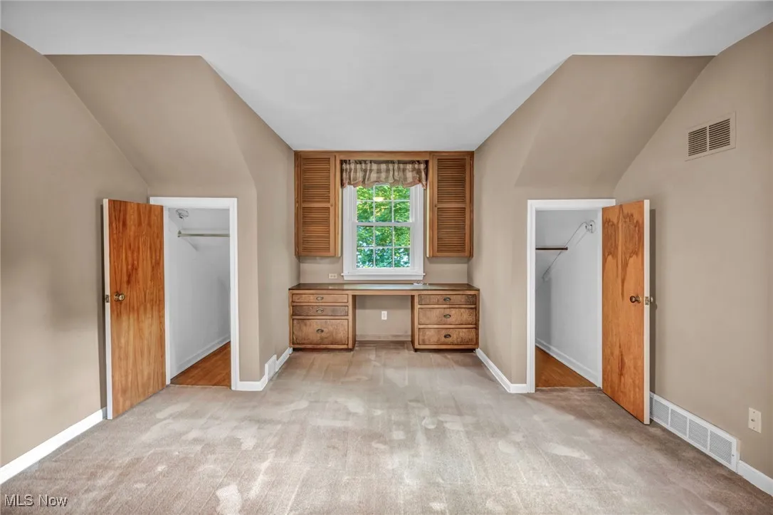  Bedroom with vaulted ceiling, light carpet, and built in desk