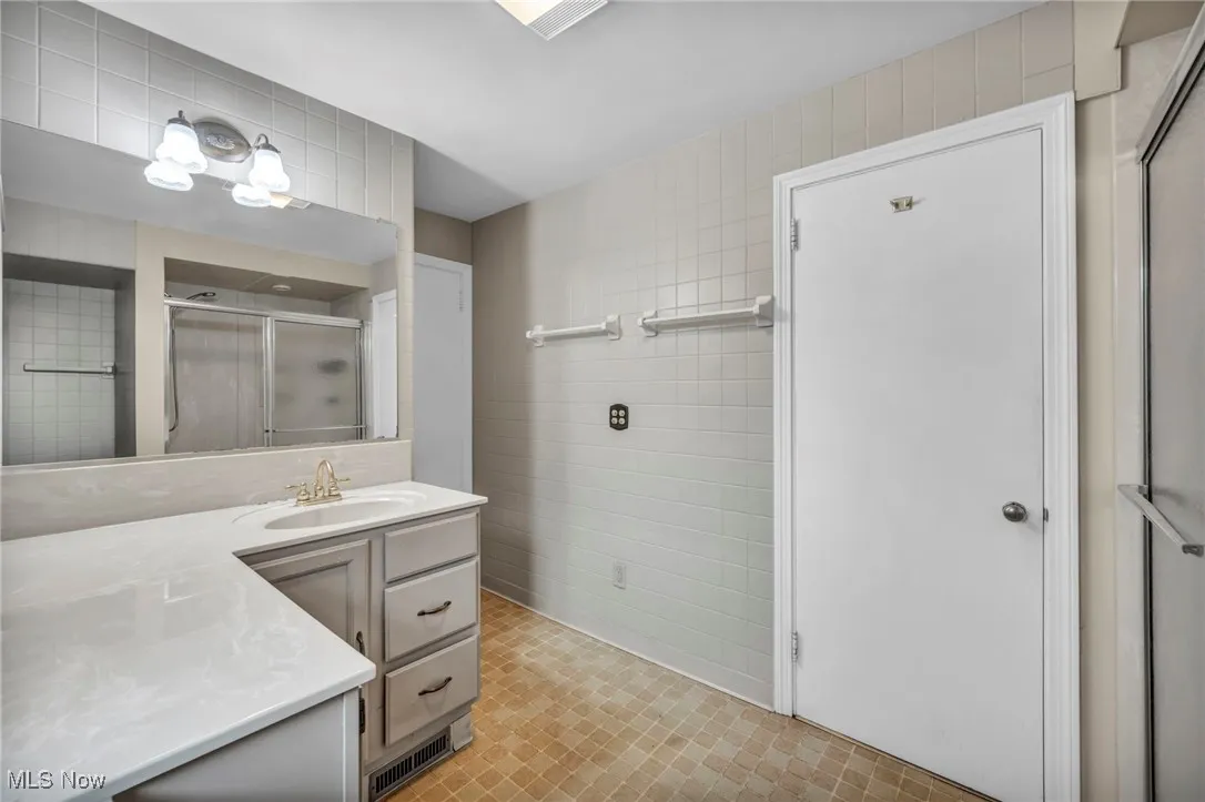 Bathroom with tile walls, vanity, and a shower stall
