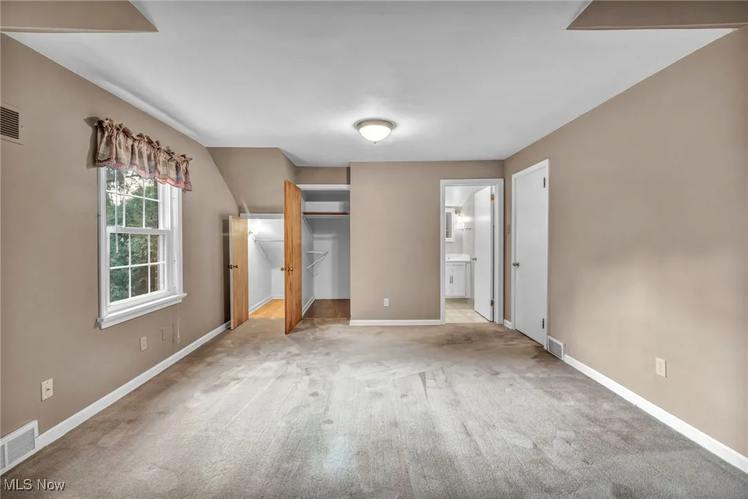Bedroom featuring a spacious closet, carpet floors, and ensuite bathroom