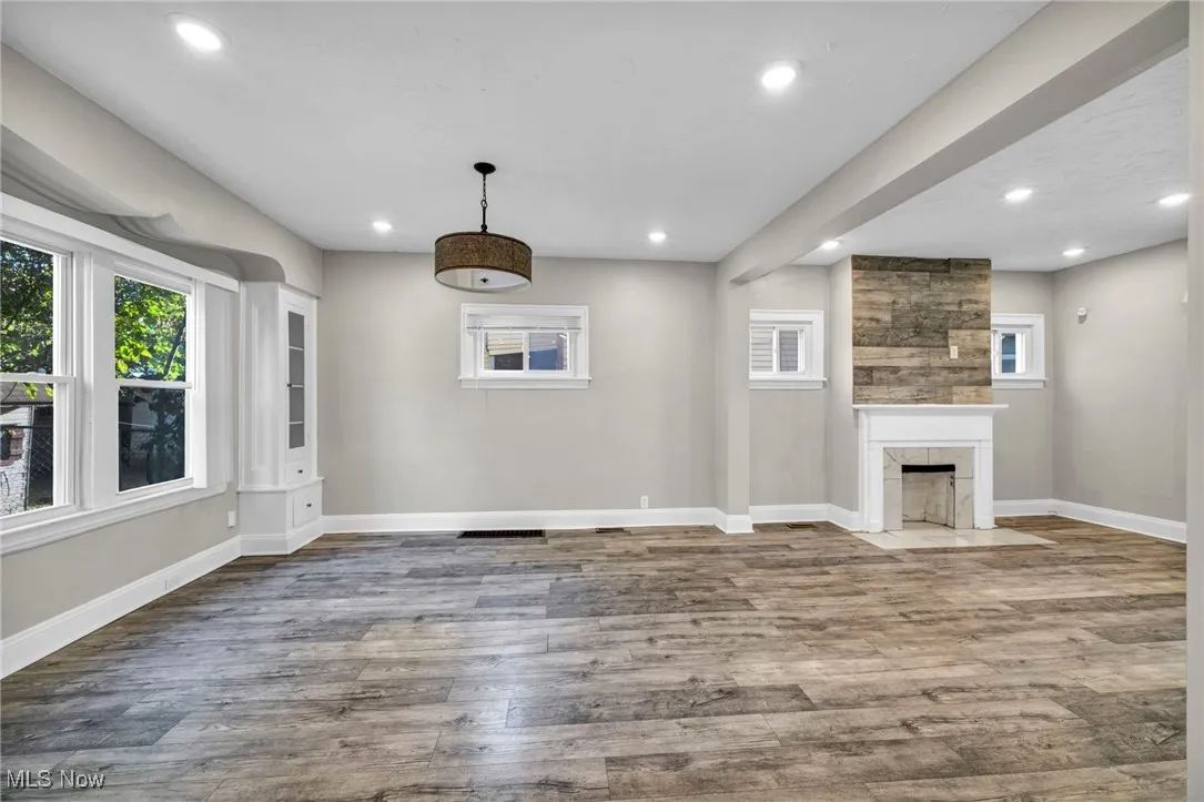 Unfurnished living room featuring wood finished floors, recessed lighting, and a high end fireplace