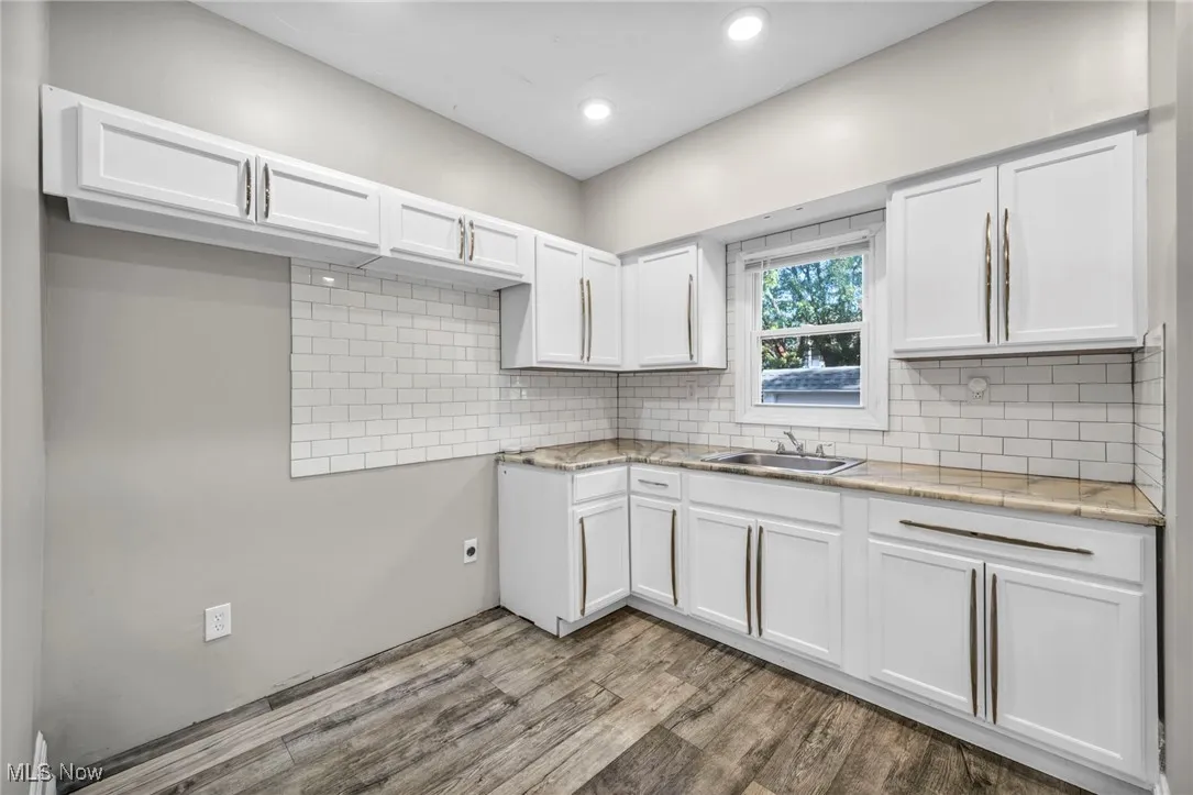 Kitchen featuring white cabinetry, light wood finished floors, decorative backsplash, recessed lighting, and light stone counters