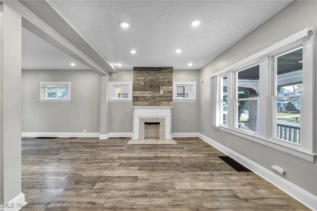 Unfurnished living room with wood finished floors, recessed lighting, and a tiled fireplace