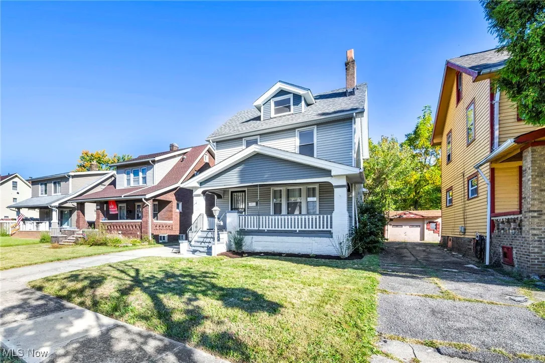 Traditional style home with a chimney, a porch, an outbuilding, a front lawn, and a detached garage