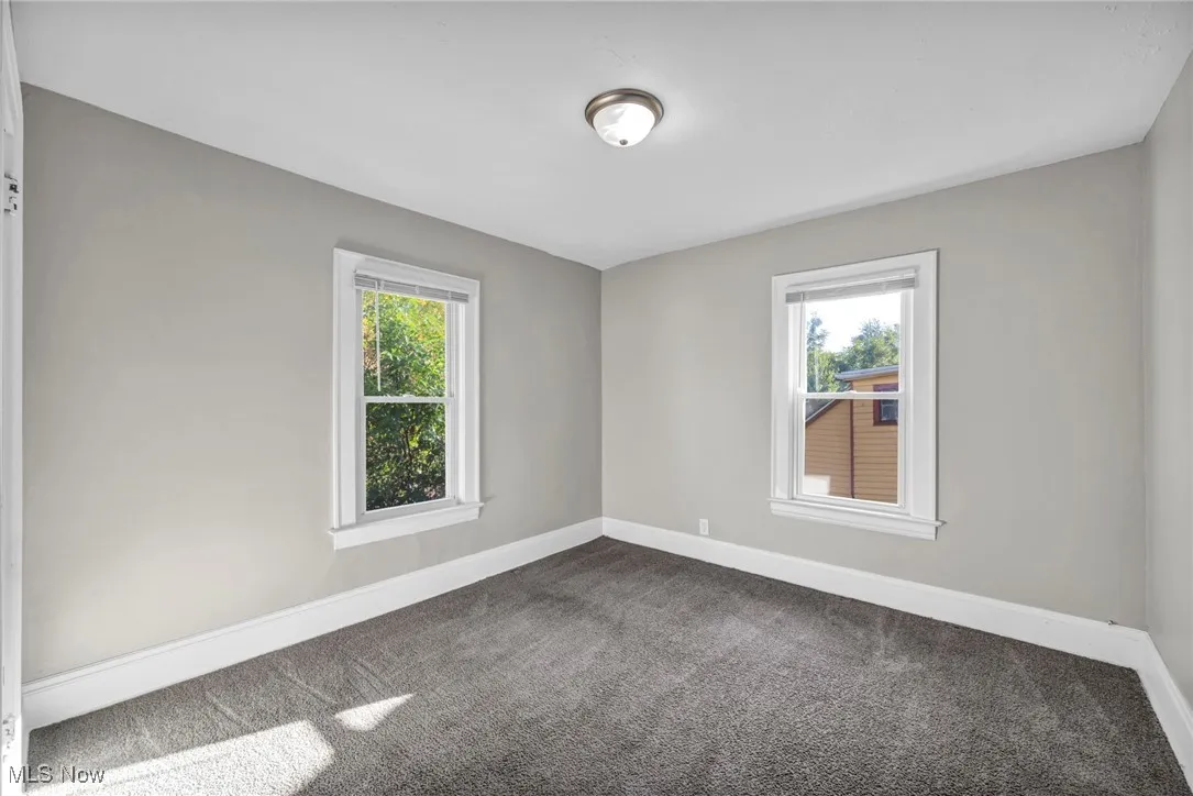 Empty room featuring dark carpet and healthy amount of natural light