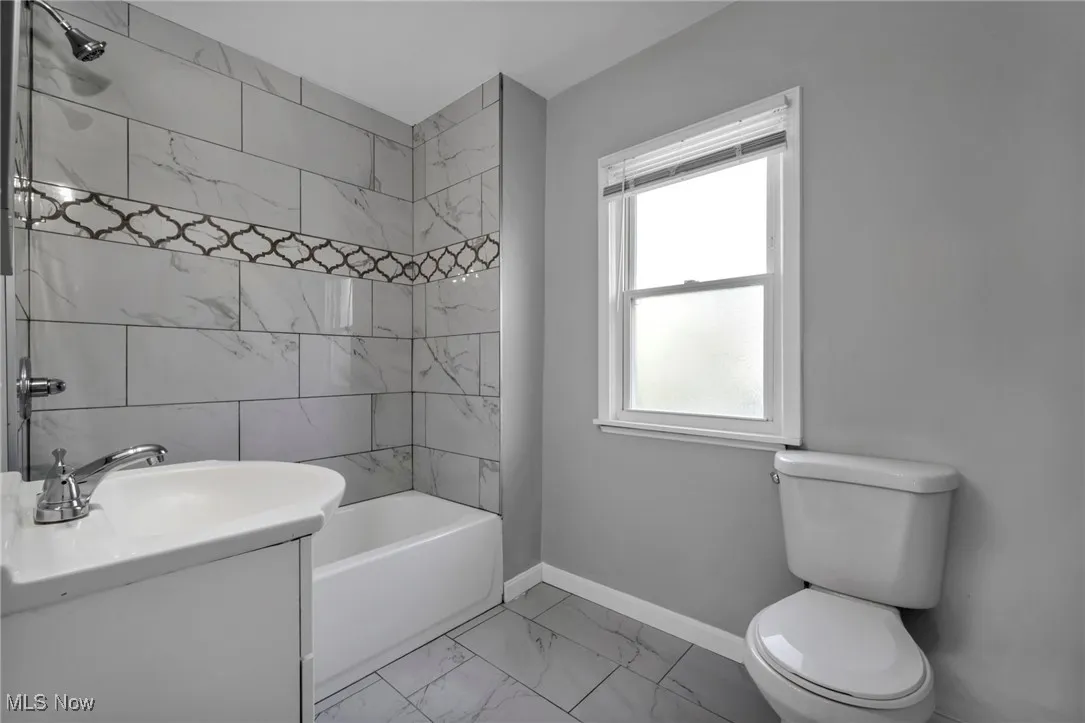 Full bathroom featuring light marble finish flooring, tub / shower combination, and vanity
