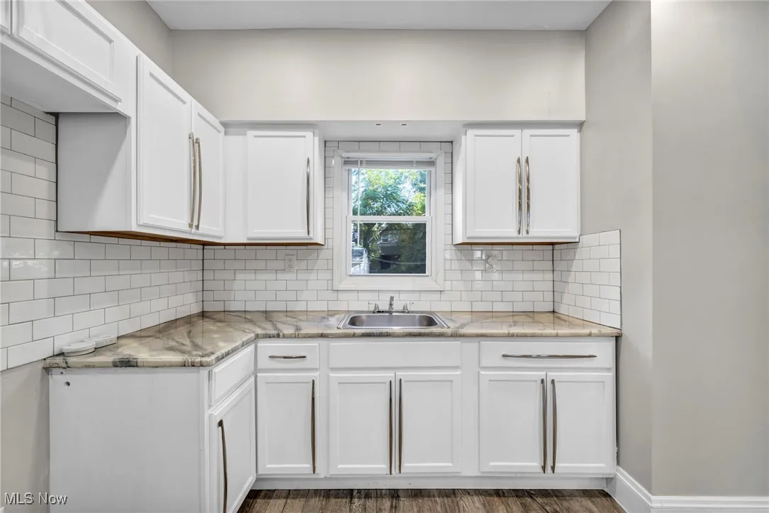 Kitchen featuring white cabinetry, tasteful backsplash, dark wood-style flooring, and light stone counters
