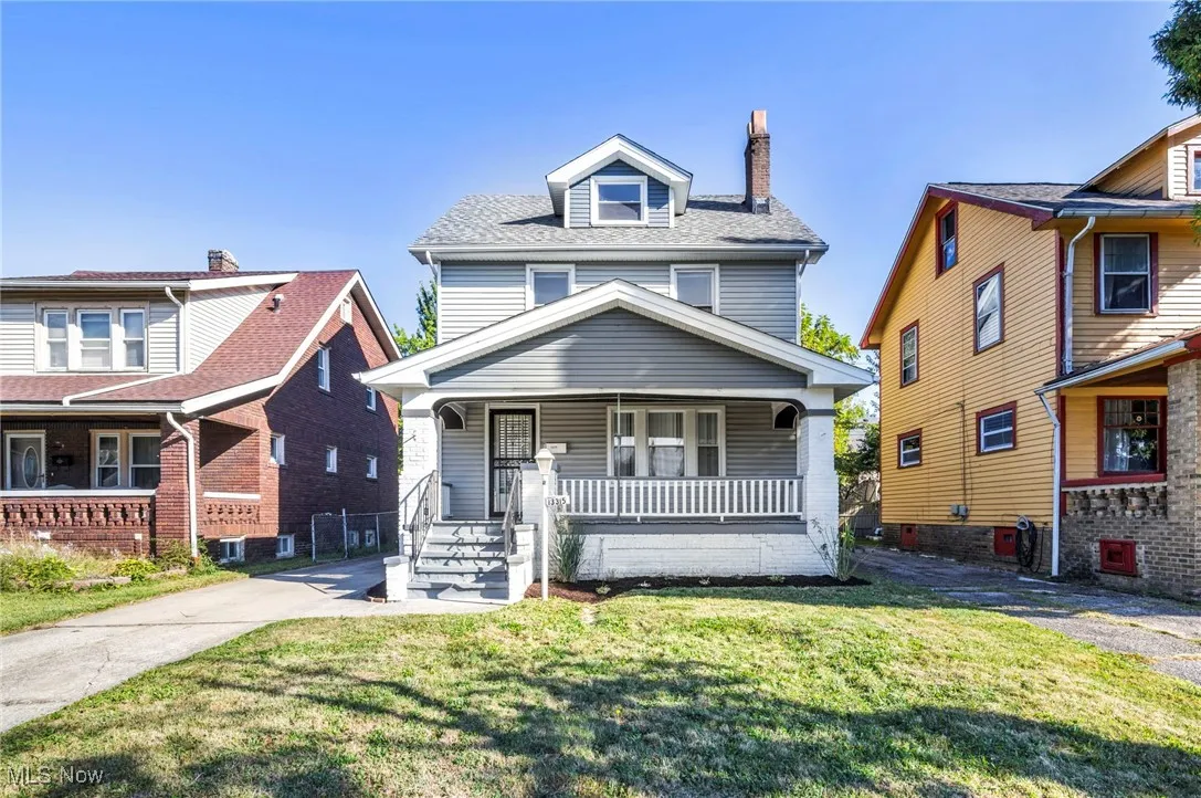 American foursquare style home featuring a porch, a chimney, a front lawn, and roof with shingles