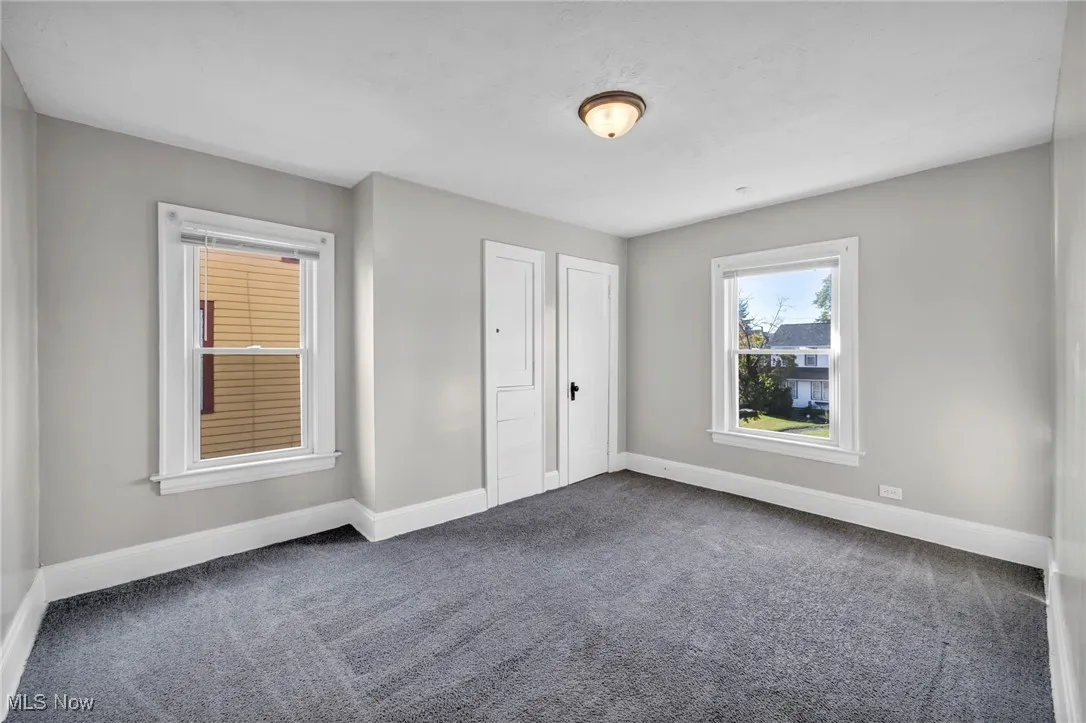 Unfurnished bedroom with dark colored carpet and baseboards