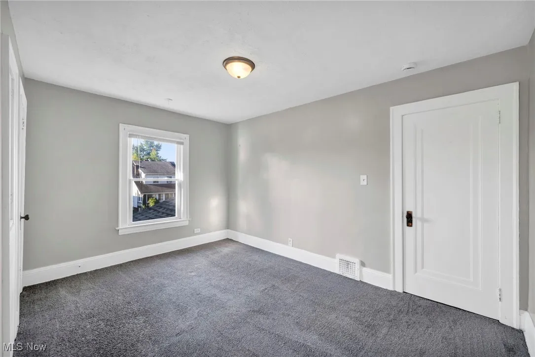 Spare room featuring dark colored carpet and baseboards