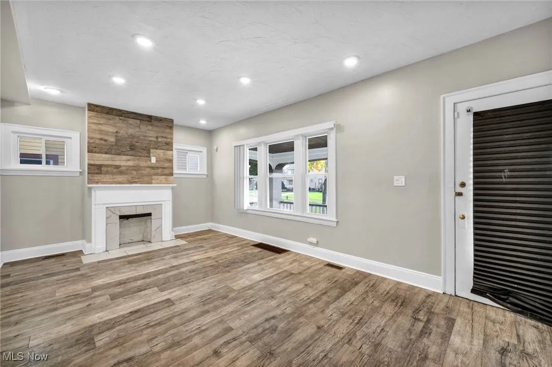 Unfurnished living room featuring light wood-style flooring, recessed lighting, a tile fireplace, and a textured ceiling