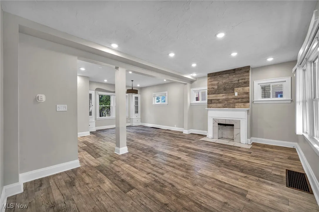Unfurnished living room with recessed lighting, dark wood-style flooring, and a tiled fireplace