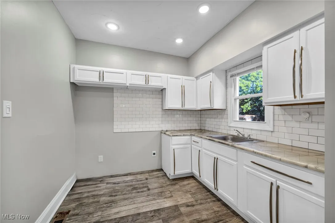 Kitchen featuring white cabinets, backsplash, dark wood finished floors, recessed lighting, and light stone countertops