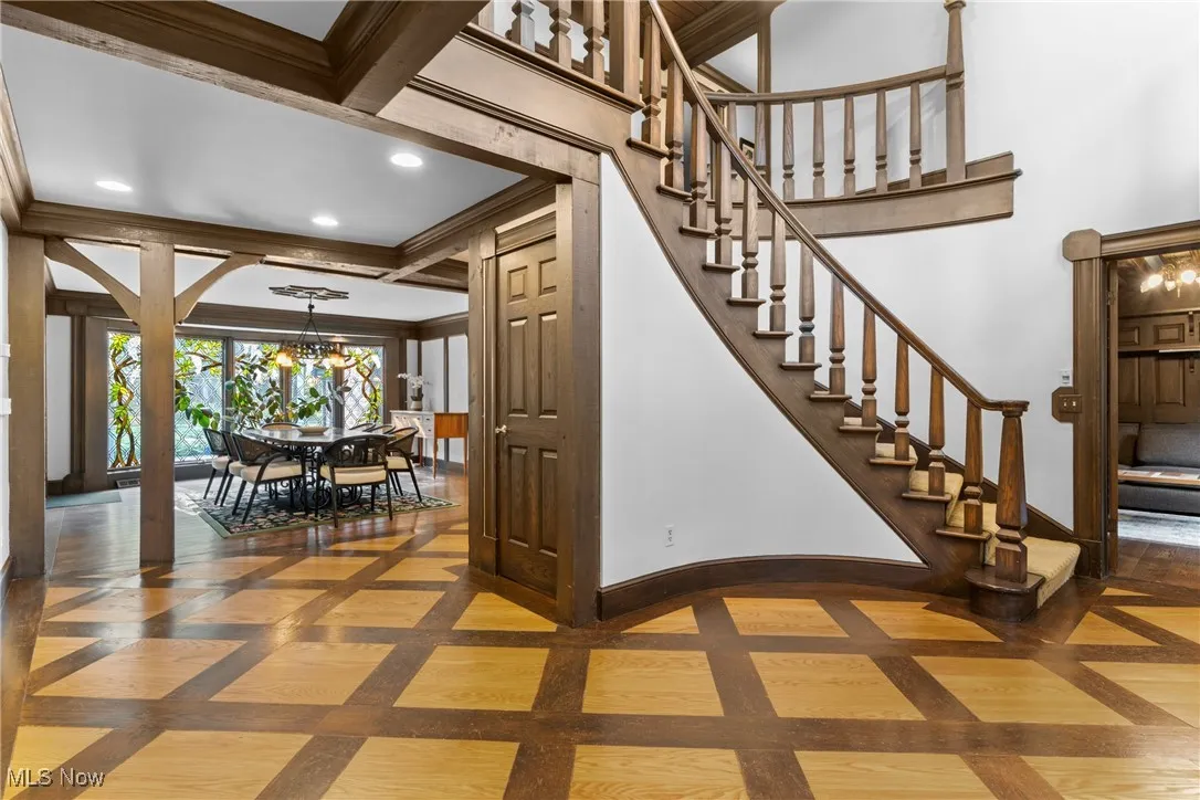 Stairway with inlaid floor details, a chandelier, recessed lighting, and beam ceiling