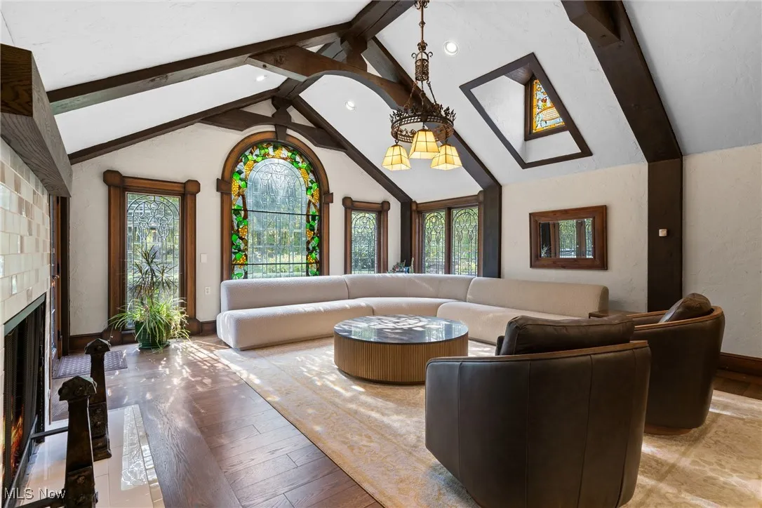 Living room with beamed ceiling, hardwood / wood-style floors, a fireplace, high vaulted ceiling, and recessed lighting