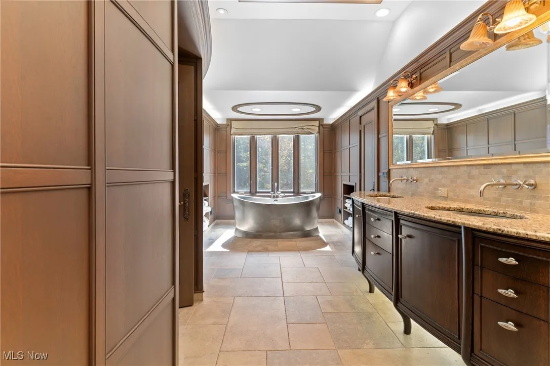 Full bathroom featuring double vanity, a soaking tub, backsplash, recessed lighting, and light tile patterned floors