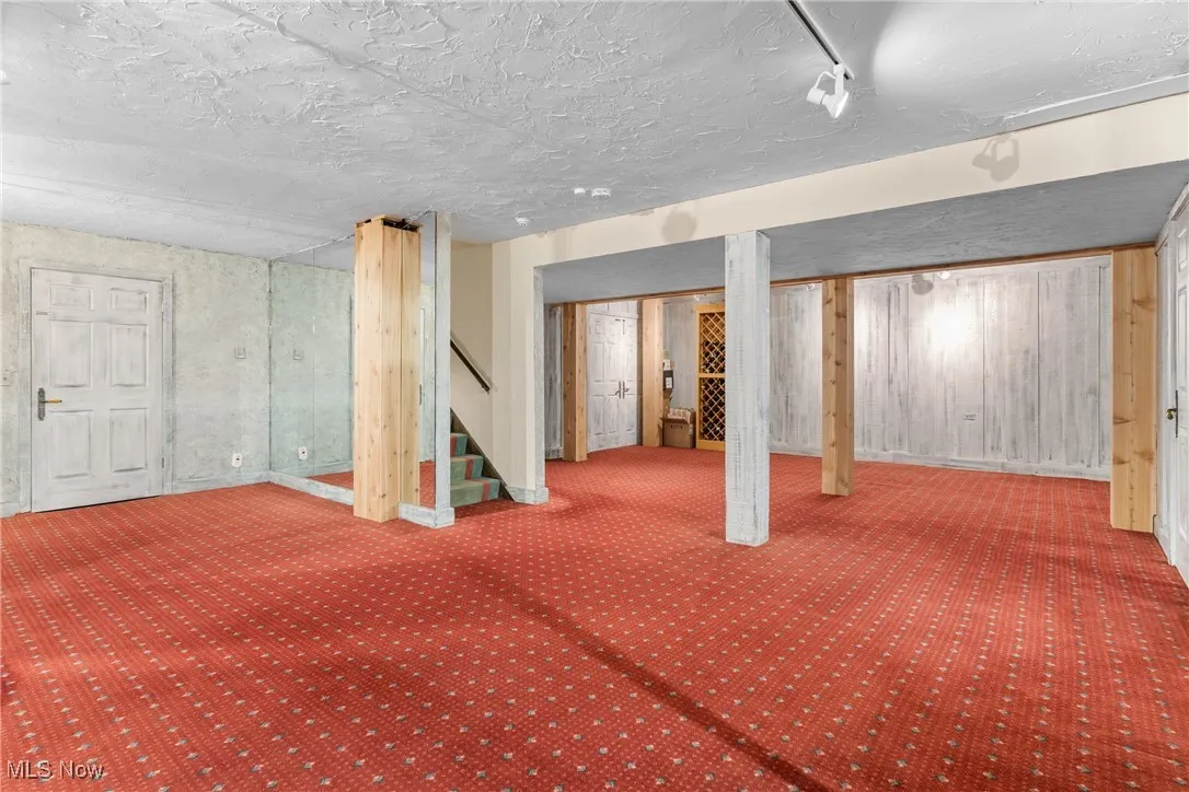 Finished below grade area with stairs, a textured ceiling, and carpet
